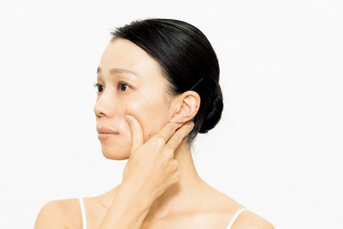 頬に親指をあてる女性