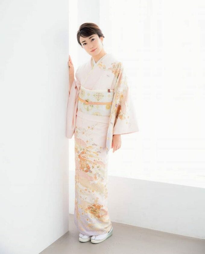 壁に寄りかかる着物の女性