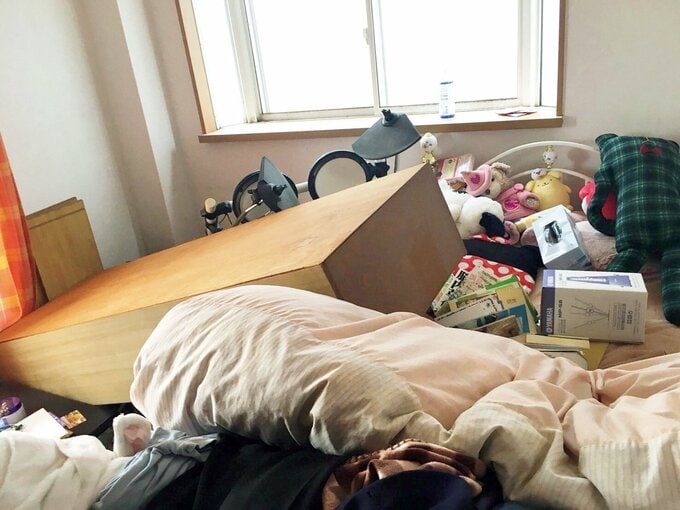 地震で家具が倒れてものが散乱している寝室