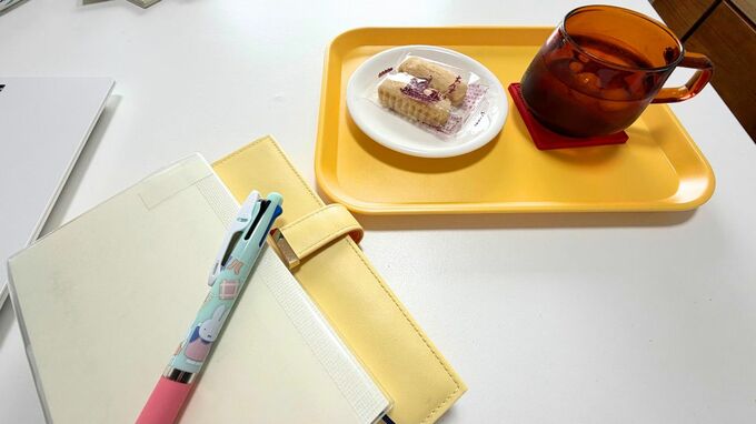 テーブルに置かれたお茶とお菓子とノート