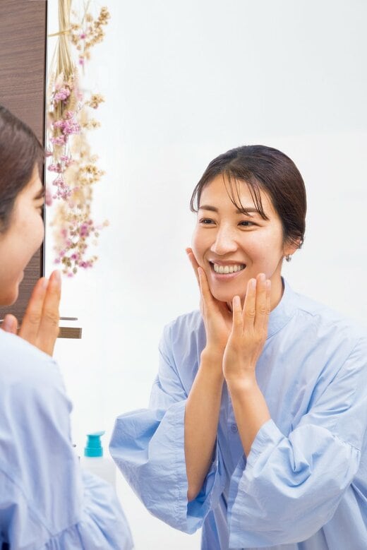 鏡を見ながらスキンケアをする女性