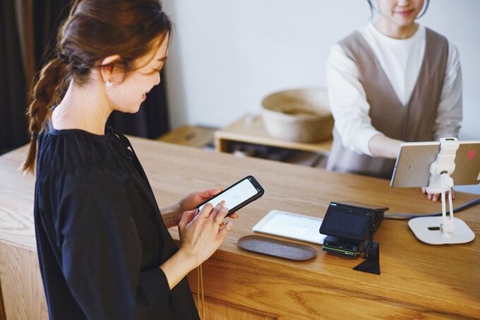 レジの前でスマホを確認する女性