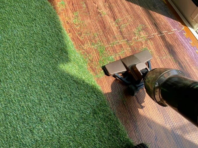 床に落ちた芝を掃除機で吸っている様子