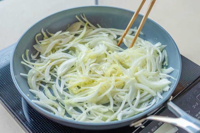 フライパンでタマネギを炒めている