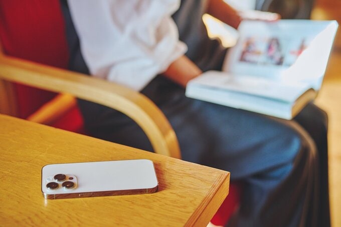 読書をする女性の手元と、机に置かれたスマホ