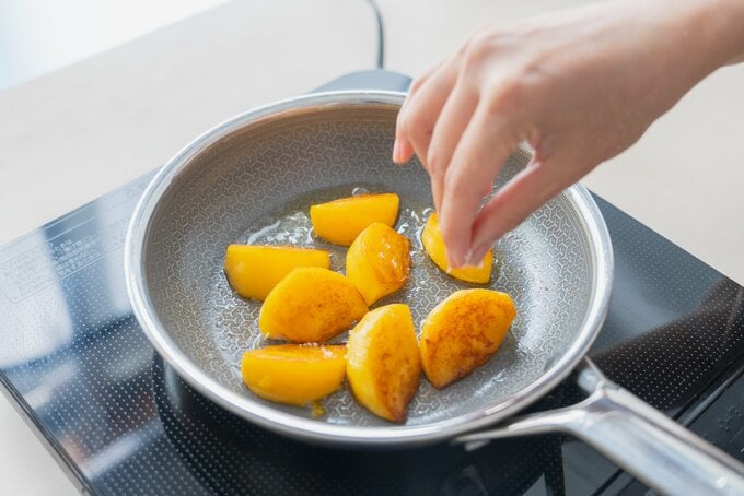 フライパンで焼いている柿に塩を振っている様子