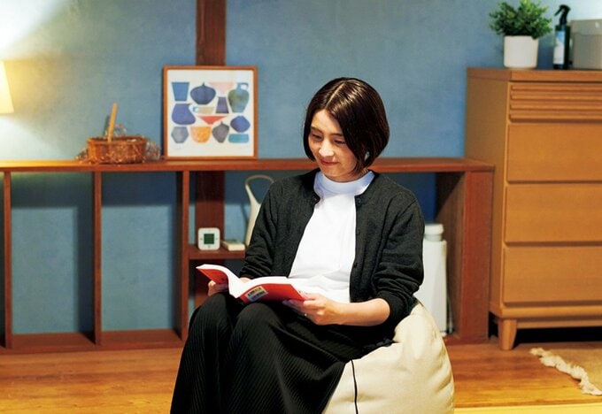 ソファに腰かけ本を読む女性