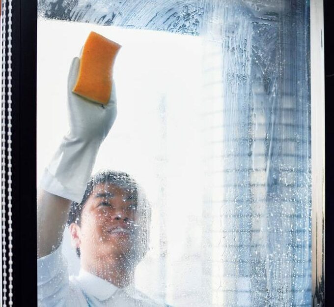 裏面の窓ガラスを磨く男性