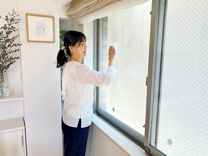 白いシャツを着た女性が窓ふきをする様子