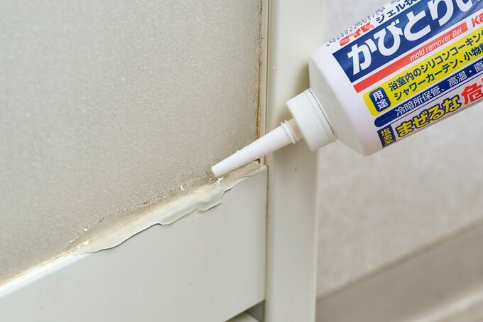 浴室ドアのパッキンにジェル状のかびとり剤を塗っている様子