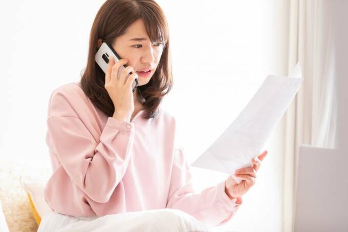 紙を持って電話をする女性