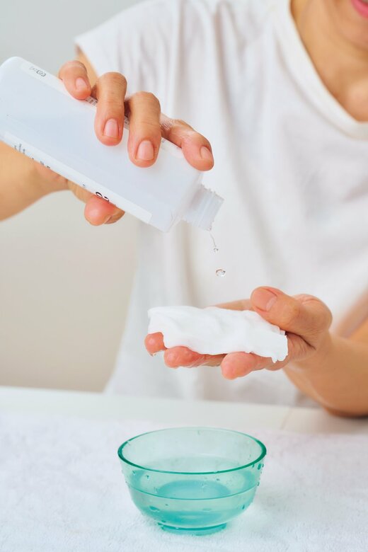 湿らせたコットンを手に乗せ、化粧水を振りかけている