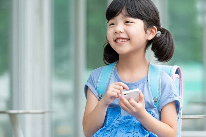 スマホを持つランドセルを背負った子ども