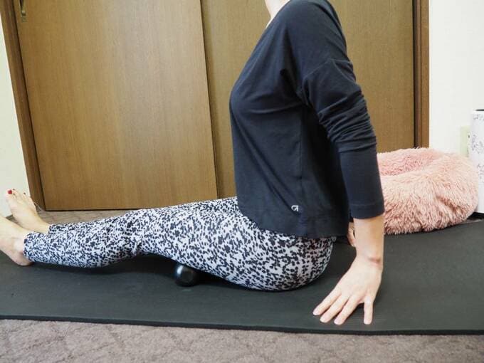太ももにツボ押しを置いて座る女性