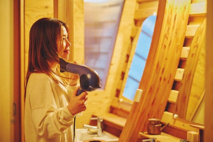 ドライヤーで髪を乾かしている女性