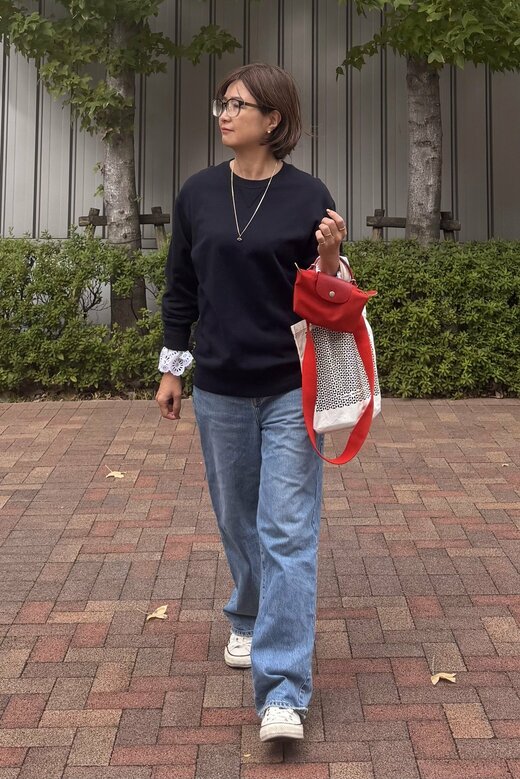 スウェットトップスにジーンズ、レースと赤のバッグを小物で