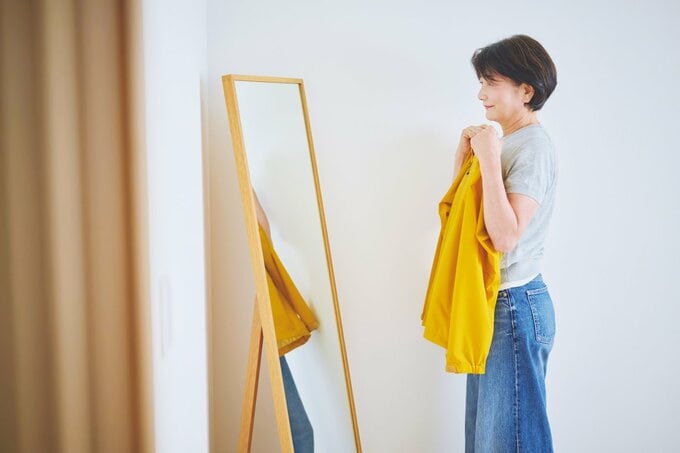 姿見に向かい黄色い服を体にあてる女性