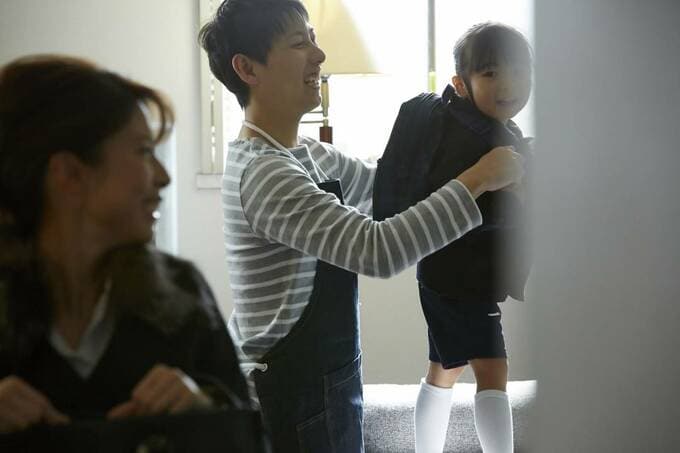 子どもの身支度を手伝う夫婦