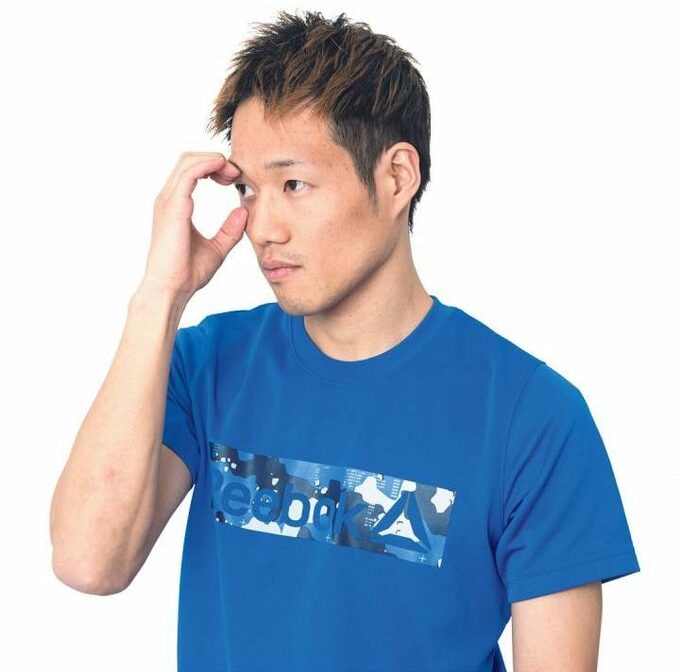 右手で右目にふれる男性