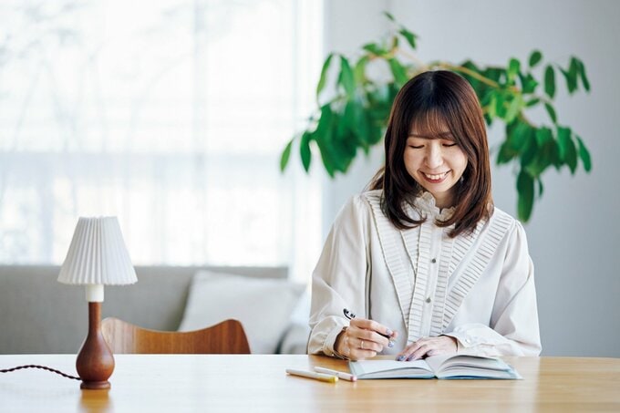 微笑みながらノートに書きこみをする白い服の女性