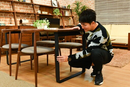テーブルの脚を触る男性
