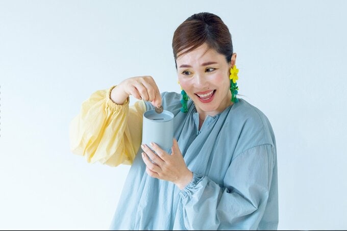 貯金箱に小銭を入れる平野ノラさん