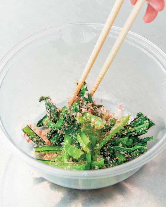 おひたしにカツオ節やすりゴマをあえる様子