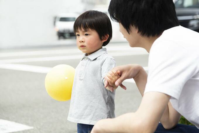 ボールを持つ子どもと子どもの手をつなぐ人