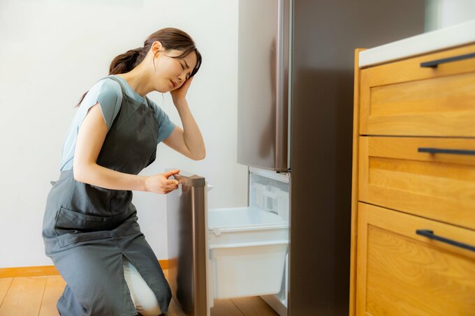 冷蔵庫を見て落ち込む女性