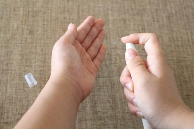 手にスプレーを吹きかける様子