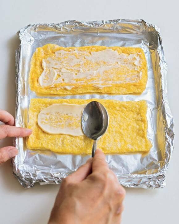 アルミホイルの上の油揚げにマヨネーズを塗る様子