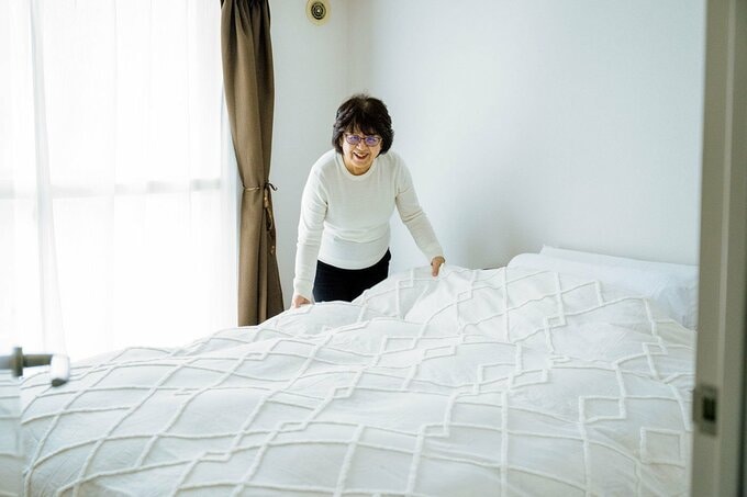 ベッドメイキングをする足立さん