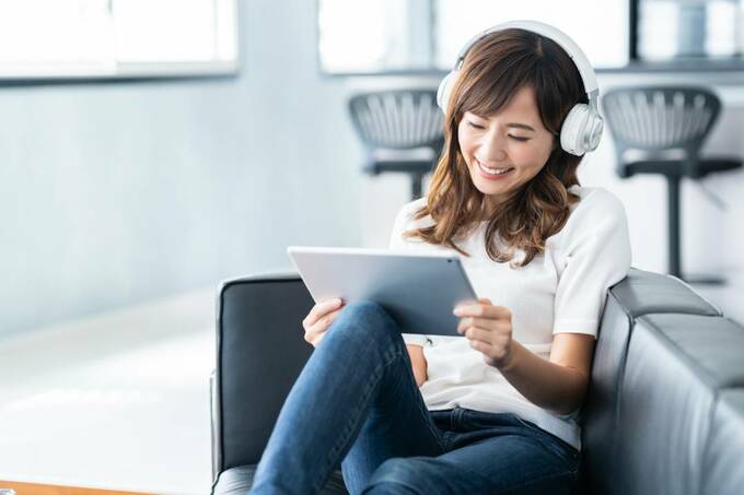 ヘッドホンをつけてタブレットを見る女性