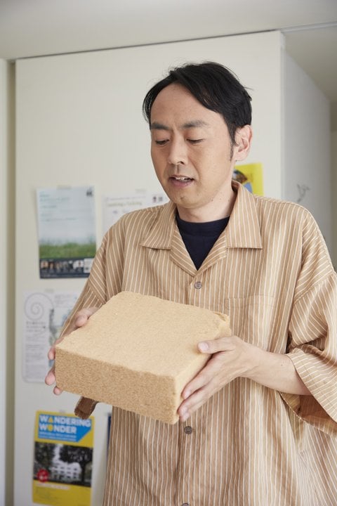 木の断熱材を持つ田中さん