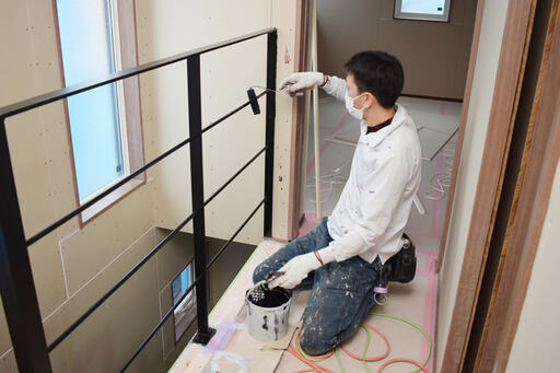 3階の手すりを塗装する職人さん