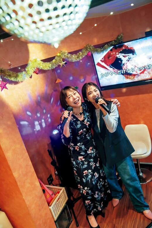 スナックで肩を組み歌う2人の女性