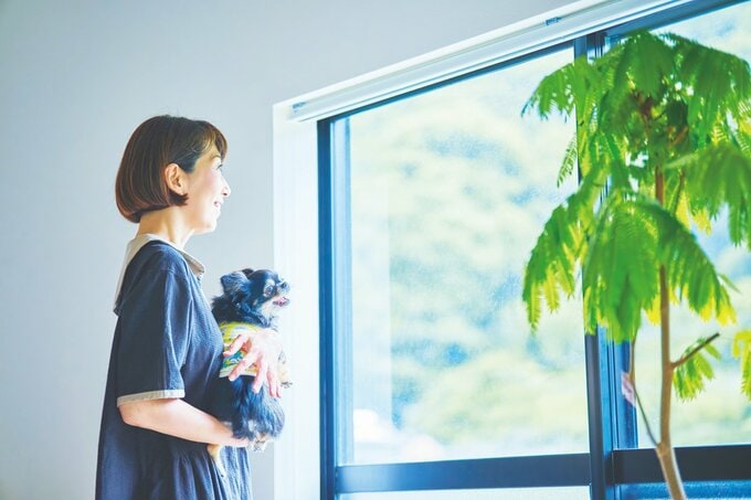 愛犬を抱っこして窓から外を見ている女性