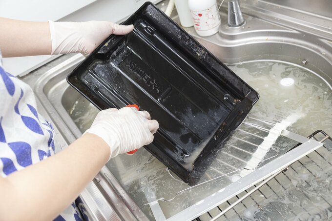 魚焼きグリルを洗う女性