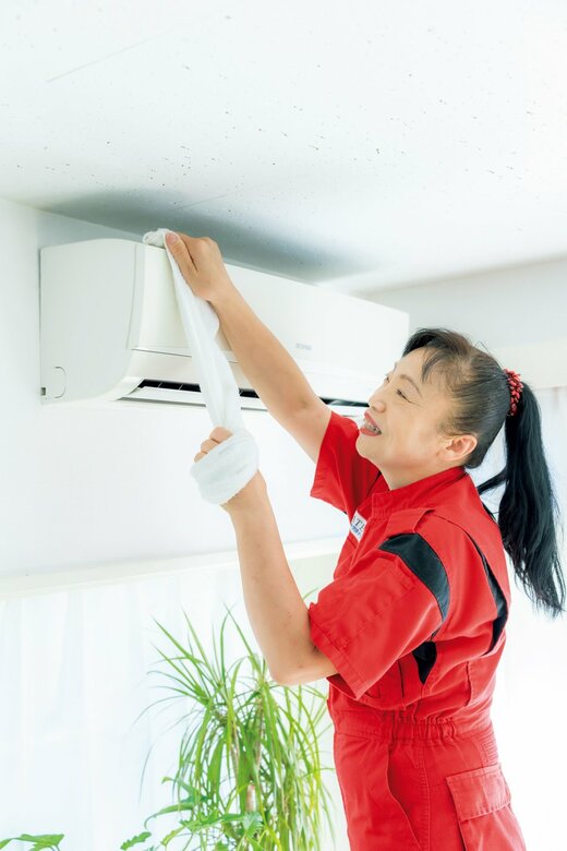 エアコン上部の掃除をしている新津さん