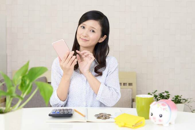 女性の前のテーブルに豚の貯金箱など