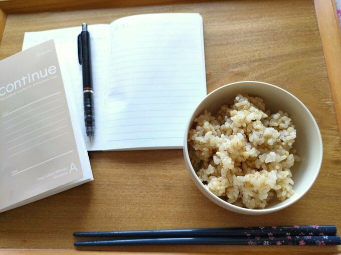 食事記録と日記を書いているA6ミニノートと、炊飯器で炊いた玄米