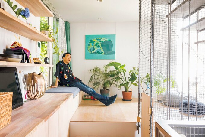 窓の前につくりつけられたソファでくつろぐ田中さん