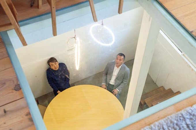ガラス床越しに1階から2階を見上げる田中さんと河内さん
