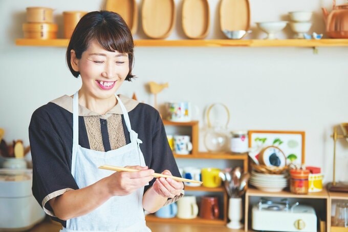 キッチン道具に微笑みかける女性