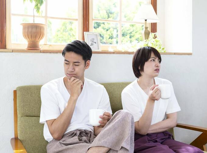 ソファで飲み物を飲む夫婦