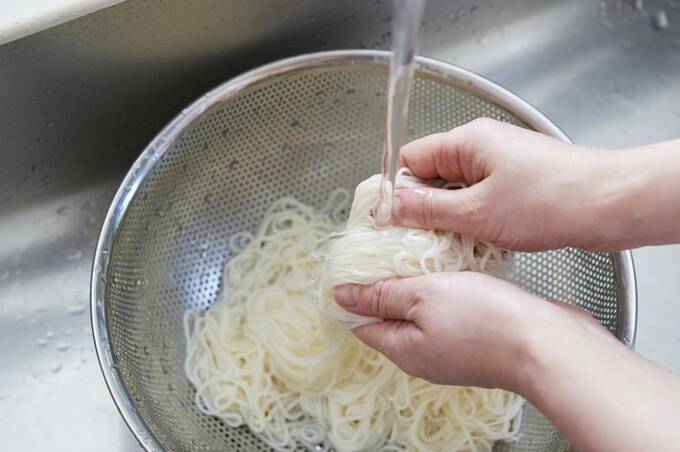 ザルの上のそうめんをもみ洗い