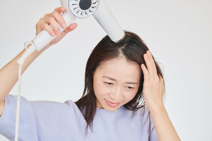 髪を引っぱって乾かす女性