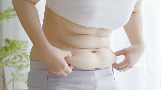 お腹をつまむ女性