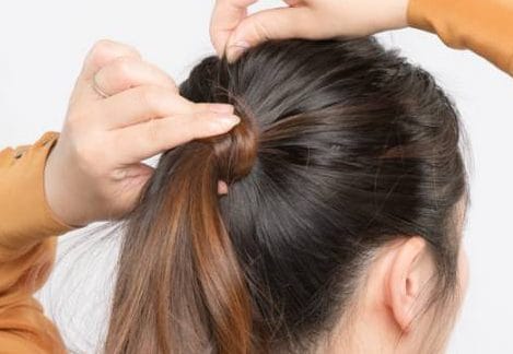 結んだ部分を手でおさえて、トップの毛束を引き出す