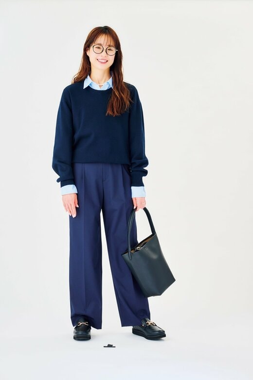 カバンを持ってほほえむパンツコーデの女性